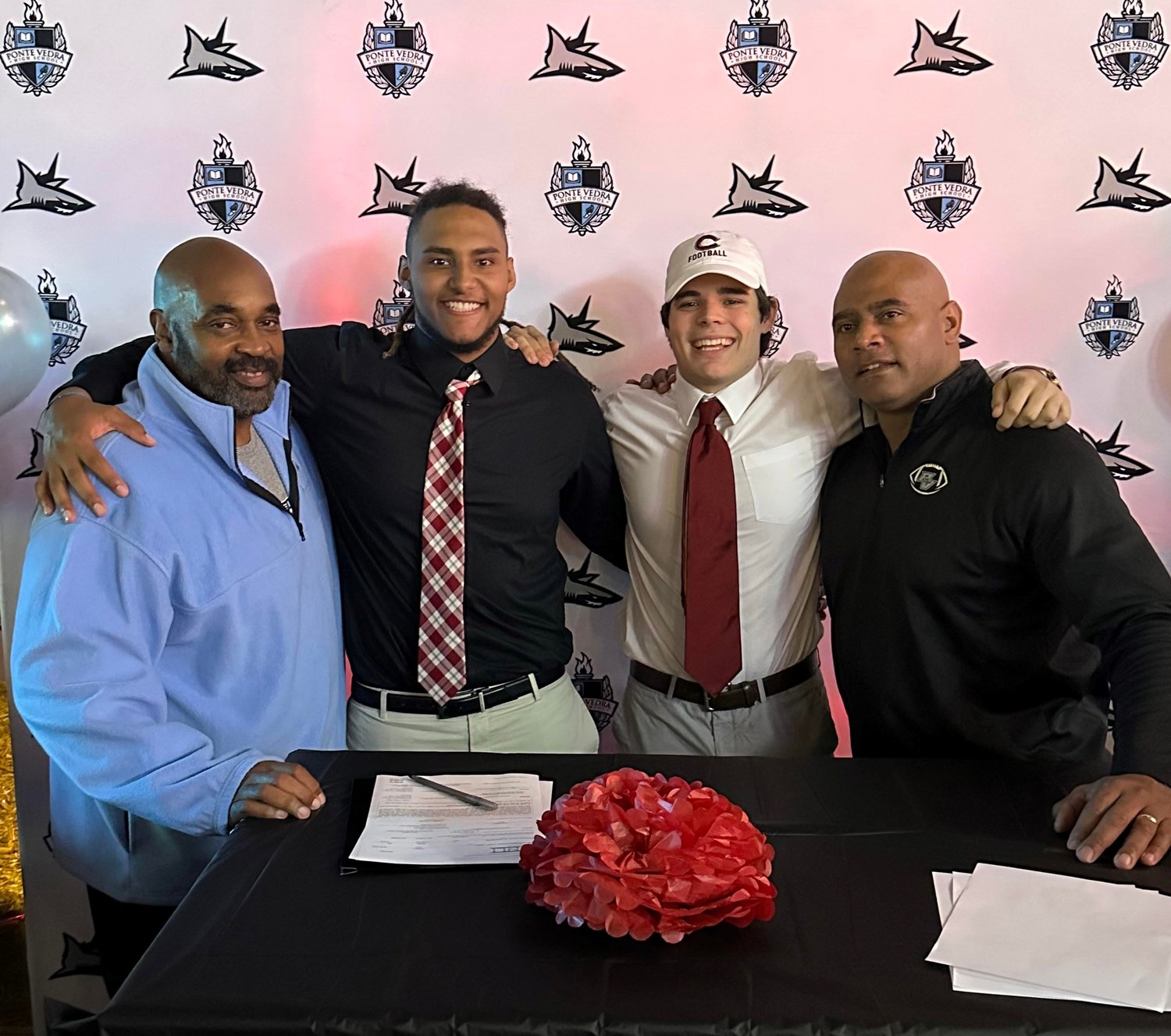 Kingston Kamal and Trooper Price share a moment with their defensive coaches after signing to play college football.